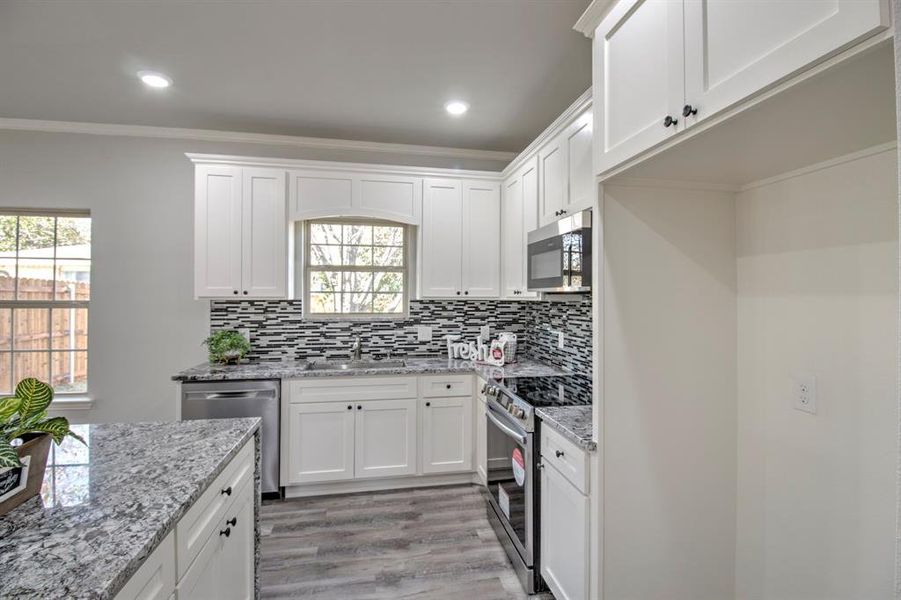 Kitchen featuring plenty of natural light, white cabinetry, and stainless steel appliances