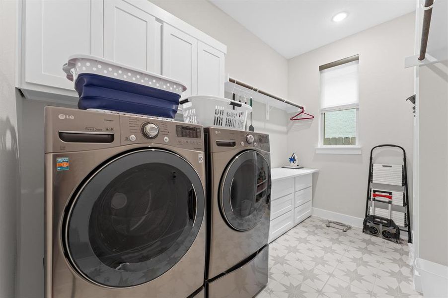 The spacious laundry room is designed for both efficiency and convenience, featuring ample cabinets for storage and organization. With plenty of countertop space and built-in hanging rods, it makes managing laundry tasks a breeze.