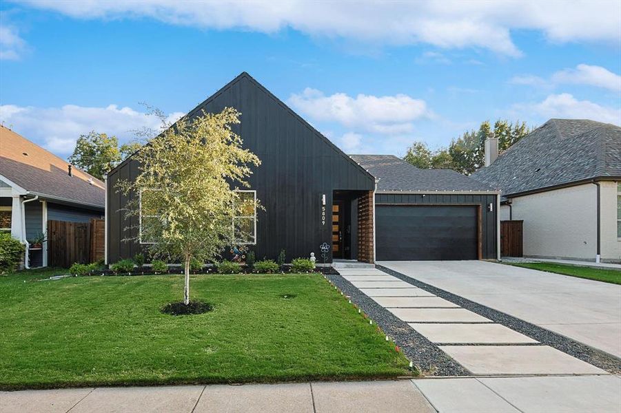 View of front of property with a garage and a front lawn