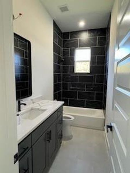 Full bathroom with vanity, toilet, and tiled shower / bath combo