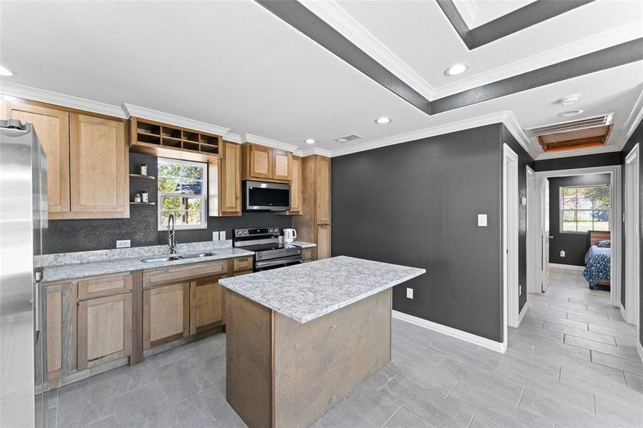 Kitchen featuring sink, stainless steel appliances, a center island, and a wealth of natural light