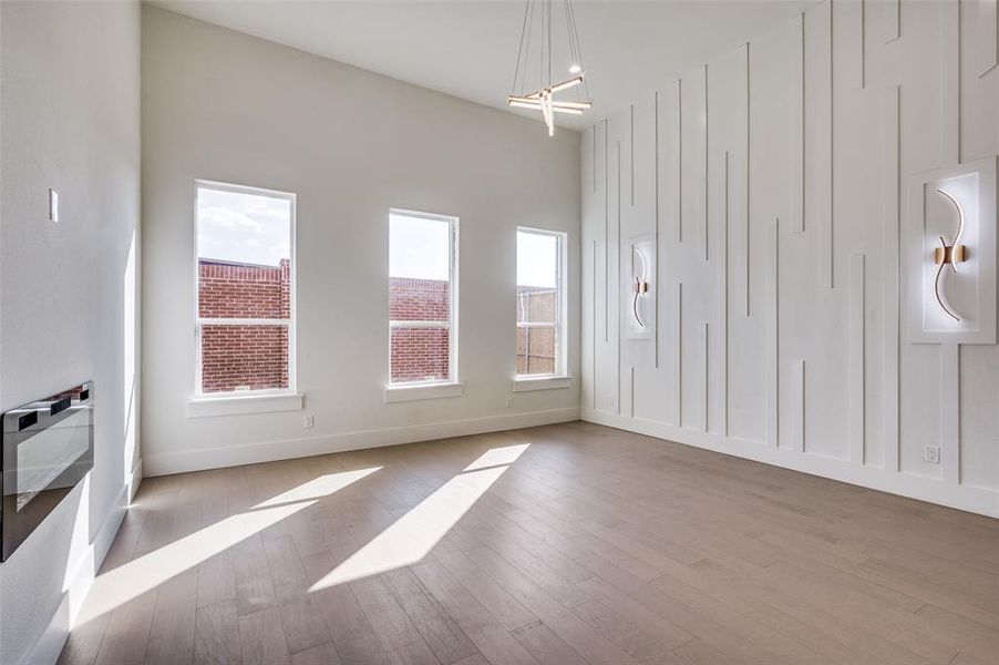 Unfurnished room with light hardwood / wood-style floors, a notable chandelier, and plenty of natural light