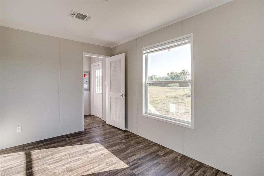 Unfurnished room with crown molding and dark wood-type flooring