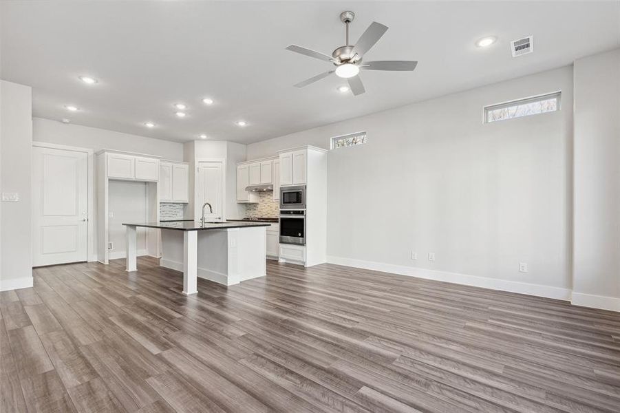 Kitchen with white cabinetry, hardwood / wood-style flooring, ceiling fan, and stainless steel appliances