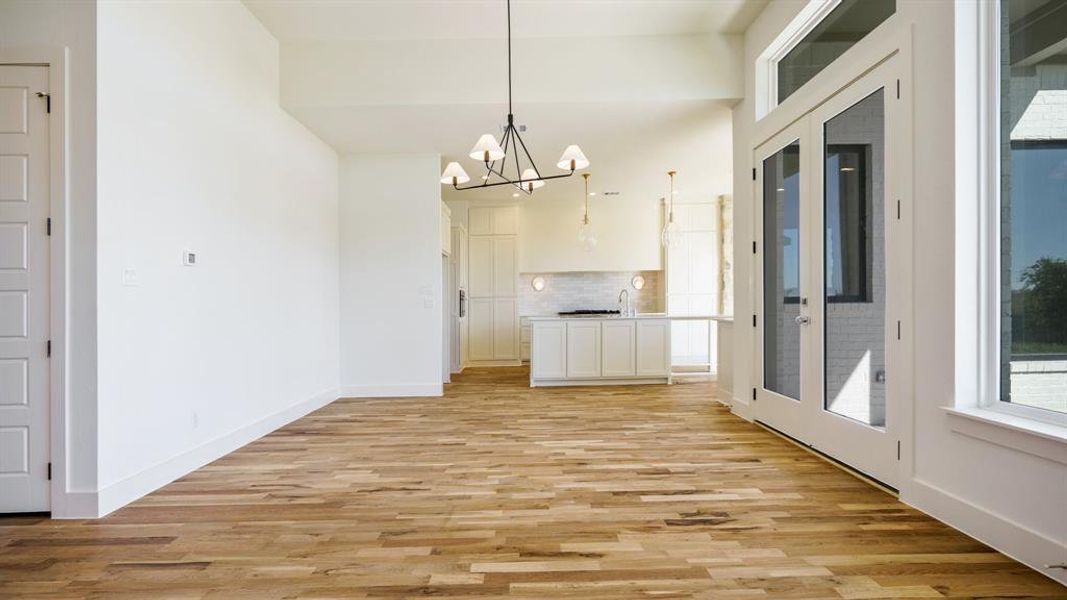 Unfurnished dining area with an inviting chandelier and light hardwood / wood-style floors