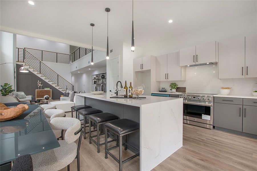 Kitchen featuring pendant lighting, light hardwood / wood-style flooring, an island with sink, electric range, and gray cabinets