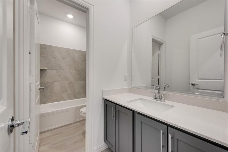 Full bathroom featuring hardwood / wood-style floors, vanity, toilet, and tiled shower / bath combo