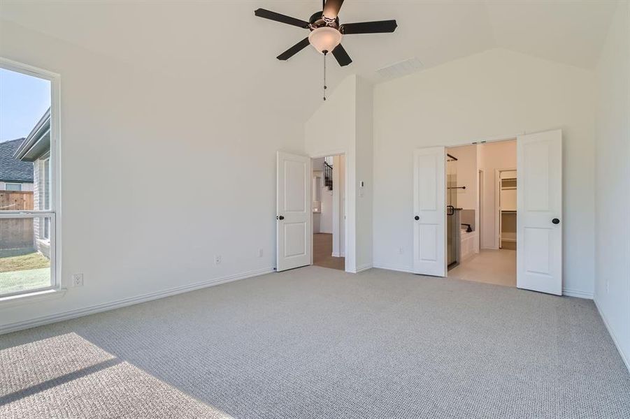 Unfurnished bedroom with light colored carpet, high vaulted ceiling, and ceiling fan