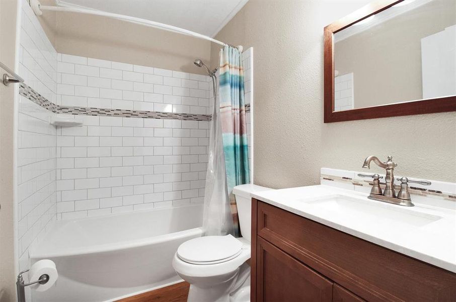 Full bathroom with shower / bath combo with shower curtain, vanity, and toilet