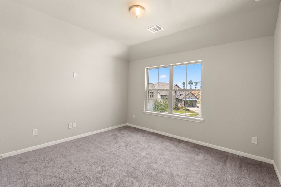 The second bedroom features plush carpet, fresh paint and a large windows.