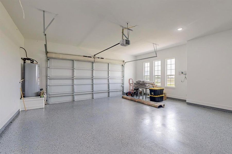 Garage featuring electric water heater and a garage door opener with epoxy floors