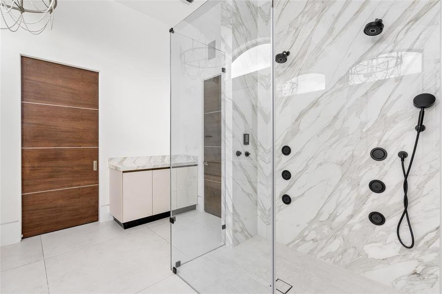 This incredible walk-in shower is equipped with the state-of-the-art Kohler DTV shower system, offering a spa-like experience with customizable water settings and precision temperature control. The sleek black fixtures beautifully contrast with the elegant tile walls, while the frameless glass enclosure enhances the room's clean and modern aesthetic.