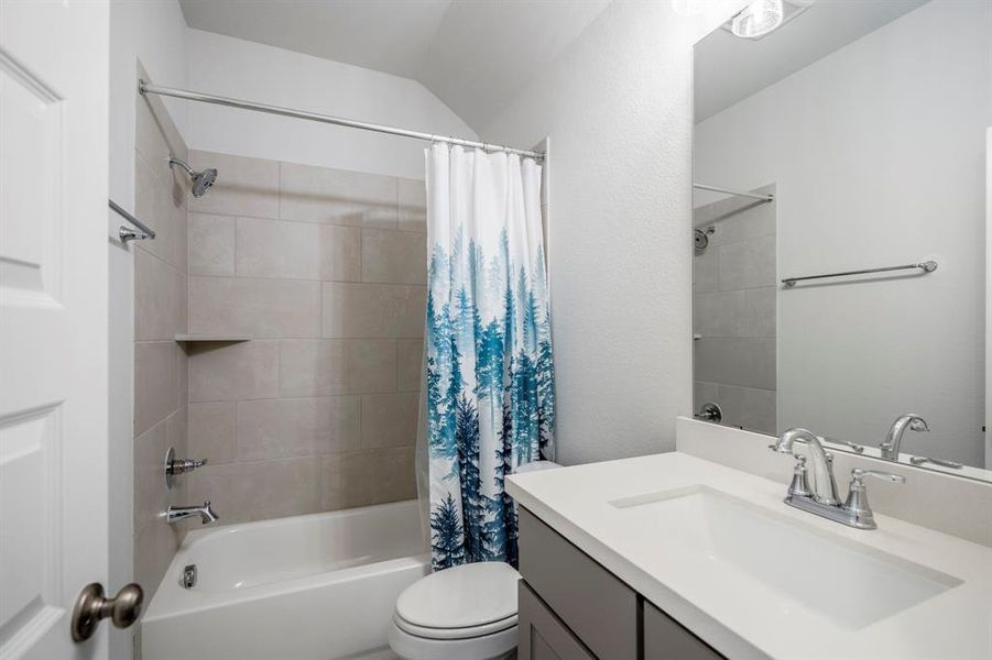 The full bathroom with gray cabinets, a spacious tub and shower, and large vanity, is located just off the private hallway of one of the secondary bedrooms, offering additional privacy.