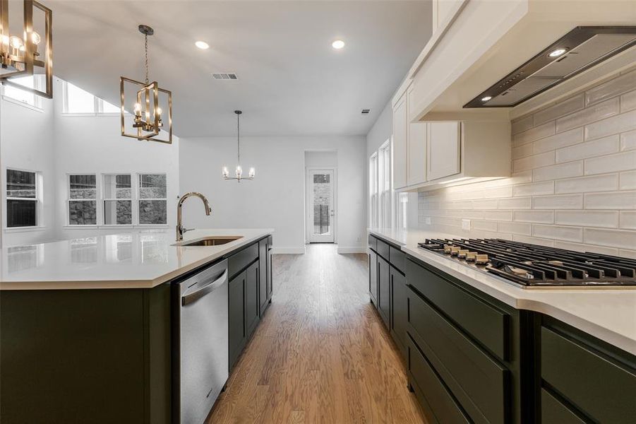 Kitchen with light hardwood / wood-style flooring, white cabinets, a kitchen island with sink, stainless steel appliances, and sink