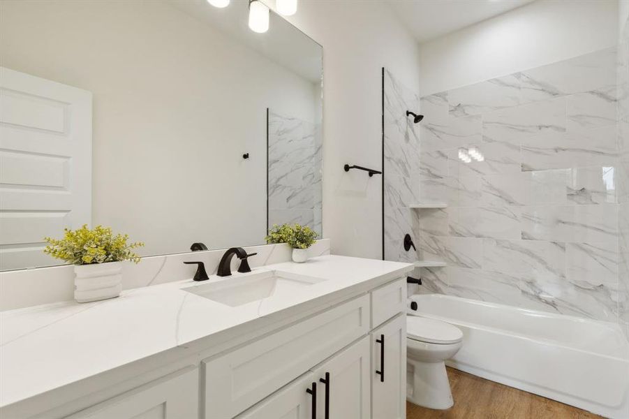 Full bathroom featuring tiled shower / bath combo, vanity, toilet, and hardwood / wood-style floors