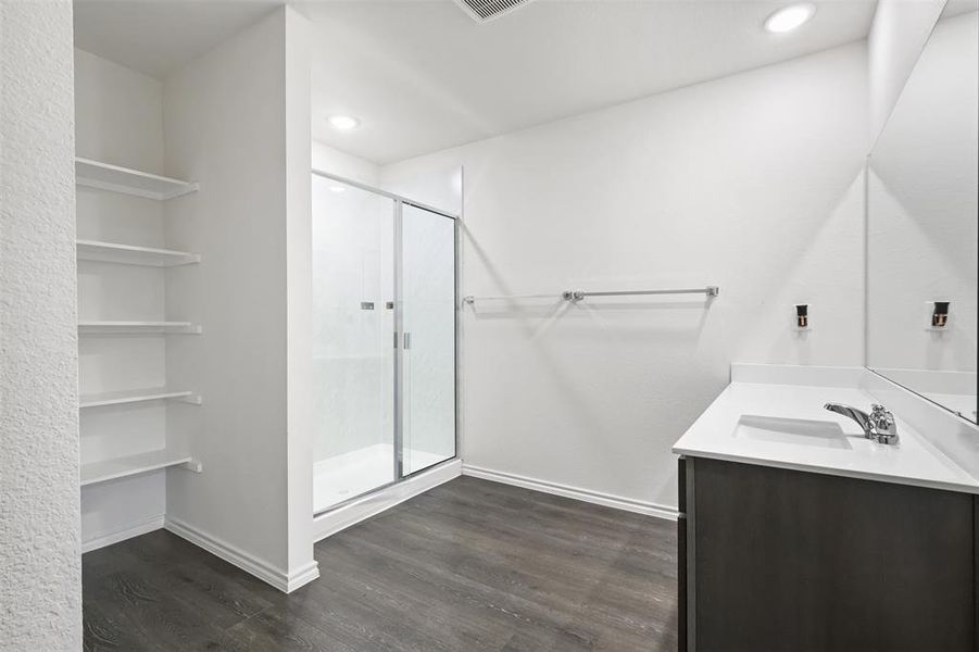 Bathroom featuring hardwood / wood-style floors, vanity, and a shower with door