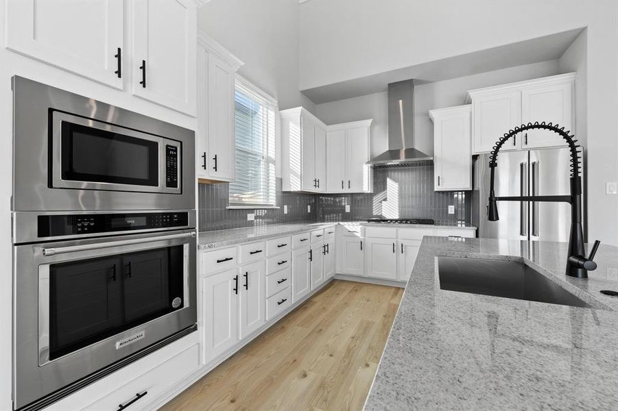 Kitchen includes a black iron cook-top with sleek, steel vent hood.