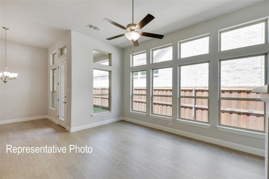 Spare room with ceiling fan with notable chandelier and light wood-type flooring