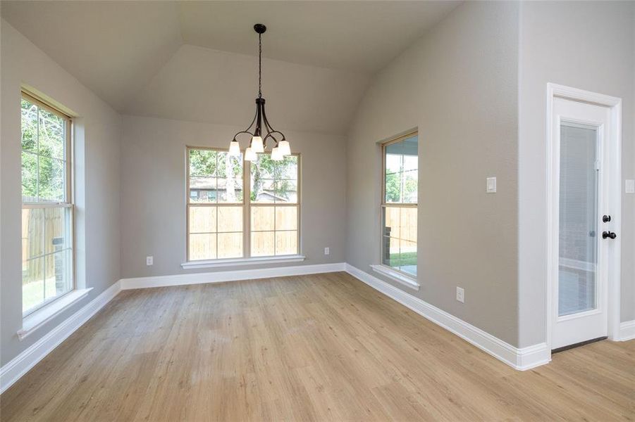 Unfurnished dining area featuring plenty of natural light, light wood-type flooring, and lofted ceiling