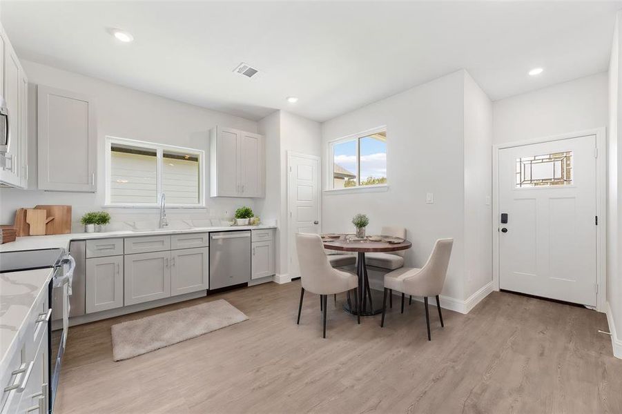 Kitchen with light stone countertops, sink, light hardwood / wood-style floors, and appliances with stainless steel finishes