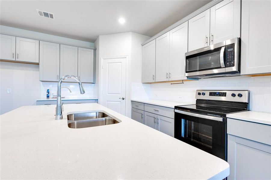 Kitchen featuring appliances with stainless steel finishes, decorative backsplash, and sink
