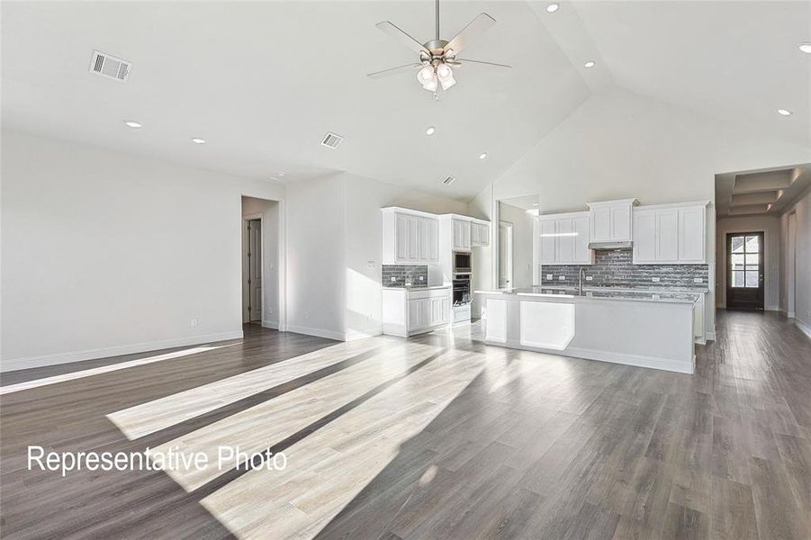 Unfurnished living room with high vaulted ceiling, ceiling fan, and hardwood / wood-style floors