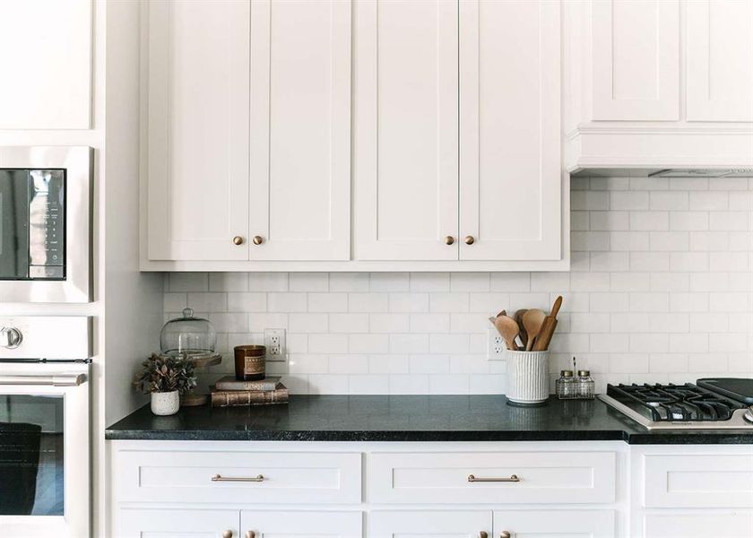 Kitchen featuring decorative backsplash, white cabinetry, and stainless steel appliances