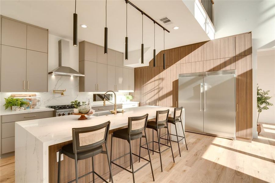 Kitchen with a kitchen island with sink, wall chimney exhaust hood, sink, appliances with stainless steel finishes, and light hardwood / wood-style floors