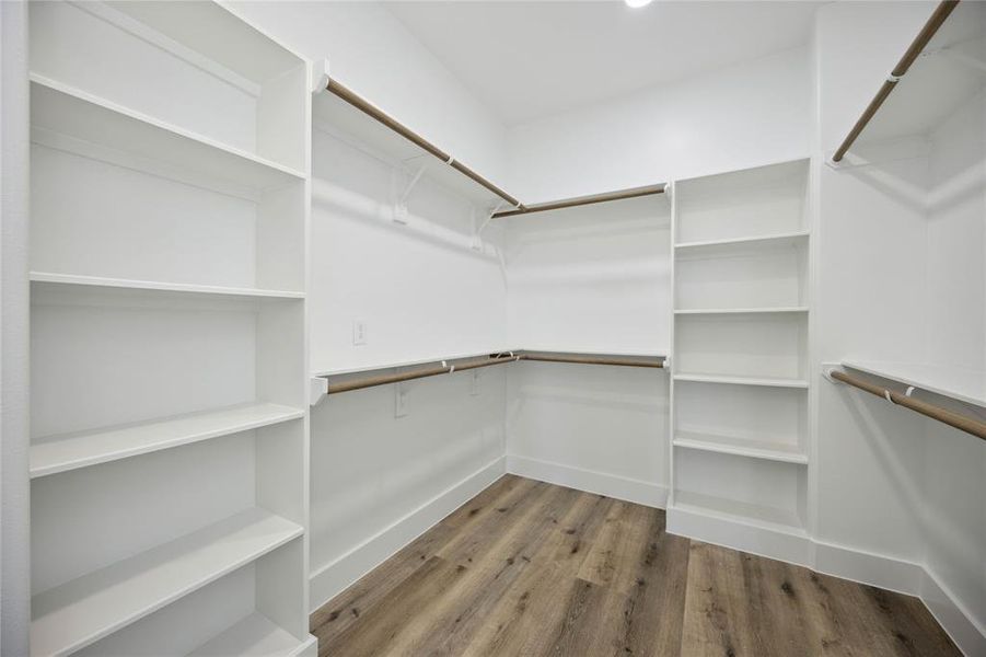 This is a spacious walk-in closet featuring ample shelving and hanging space, with a clean, modern design and neutral flooring.