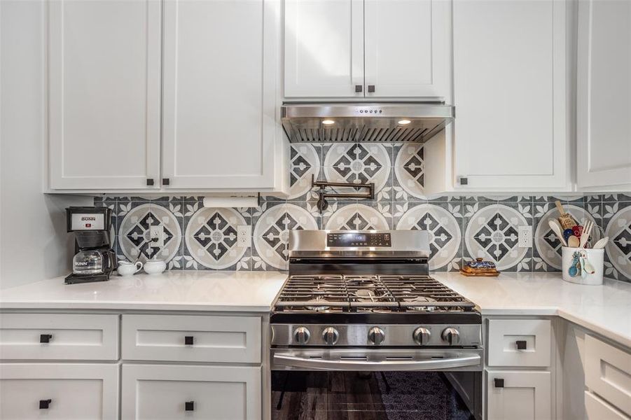 View of gas range, pot  
filler, quartz countertop