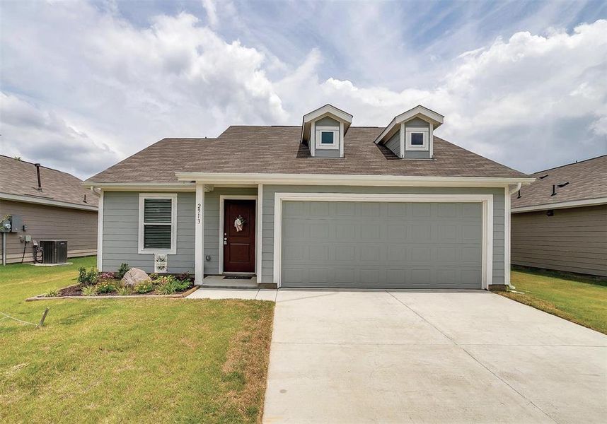 View of front of home with a garage, central AC unit, and a front lawn