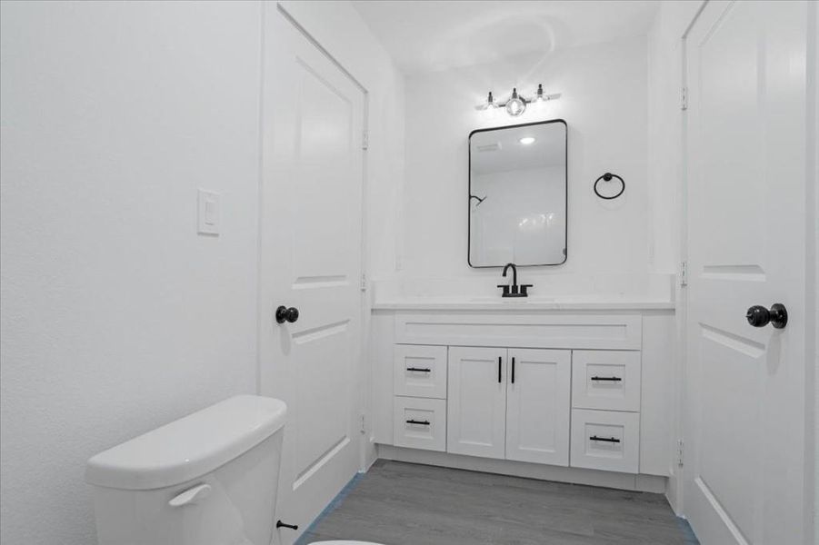 Bathroom featuring wood-type flooring, toilet, and vanity