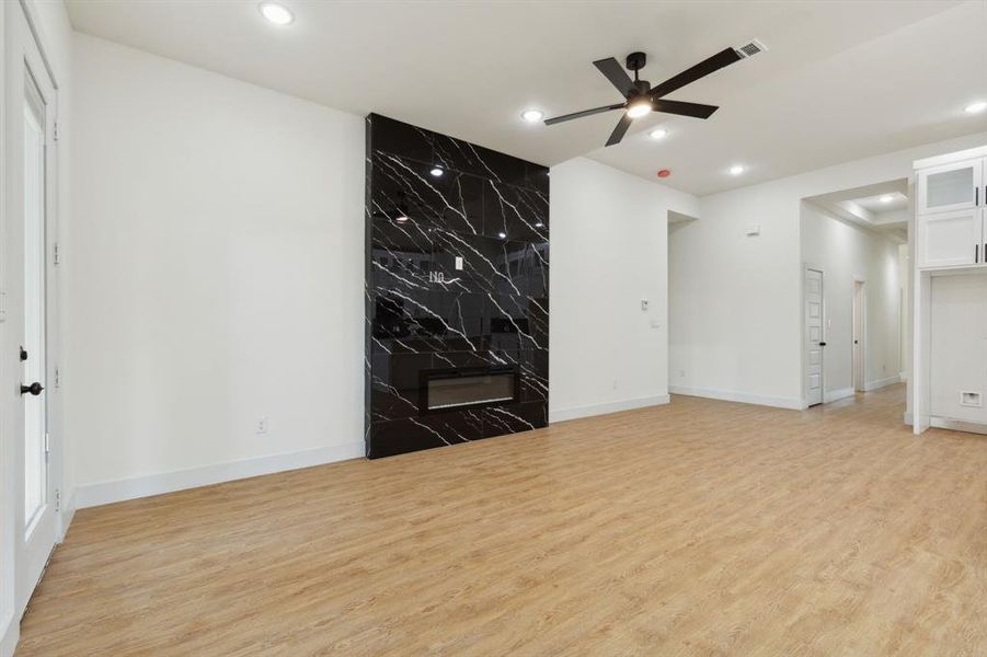 Unfurnished living room with light hardwood / wood-style flooring, ceiling fan, and a high end fireplace