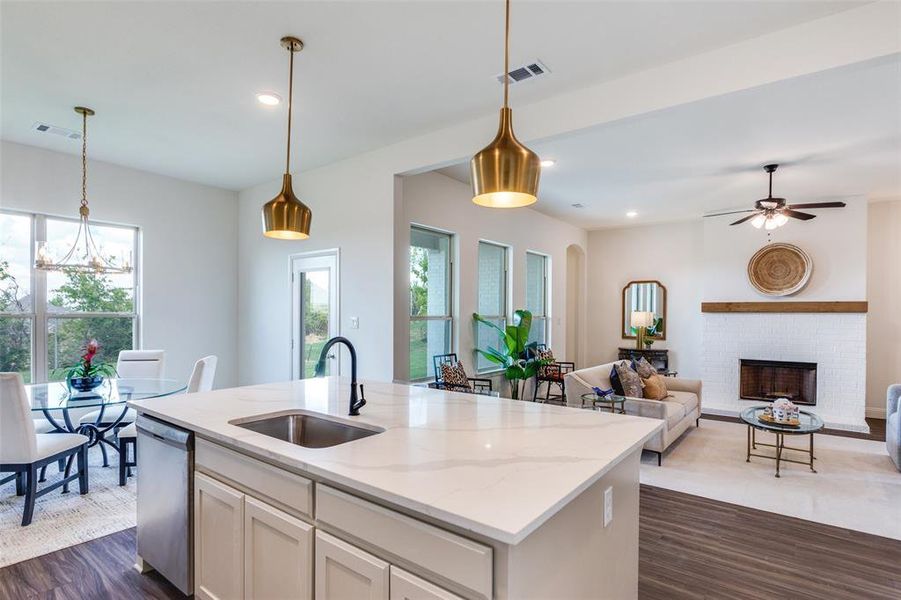 Kitchen featuring a brick fireplace, dark hardwood / wood-style flooring, sink, a kitchen island with sink, and stainless steel dishwasher