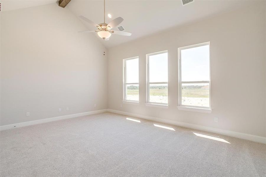 Empty room featuring beamed ceiling, carpet, high vaulted ceiling, and ceiling fan