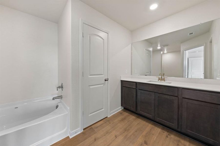 Bathroom with vanity, a tub to relax in, and wood-style flooring