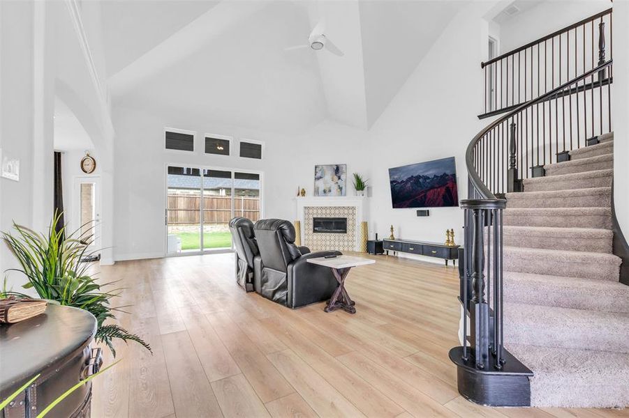 Living room with high vaulted ceiling, a tile fireplace, and light luxury vinyl plank flooring