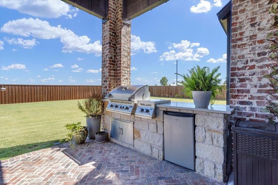 View of patio with an outdoor kitchen and a grill