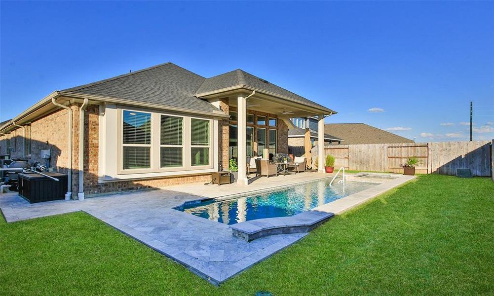 This is a modern single-story home featuring a covered patio and an inviting swimming pool with a neatly manicured lawn, perfect for outdoor relaxation and entertainment.