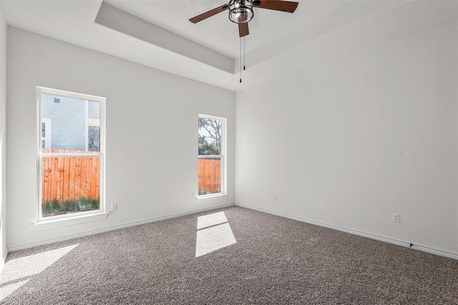 Spare room featuring carpet floors, ceiling fan, and a raised ceiling