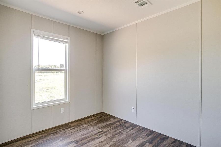 Unfurnished room featuring ornamental molding and dark hardwood / wood-style flooring