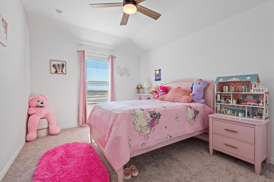 Carpeted bedroom featuring vaulted ceiling and ceiling fan