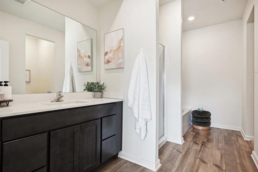 Bathroom with plus walk in shower, hardwood / wood-style flooring, and vanity