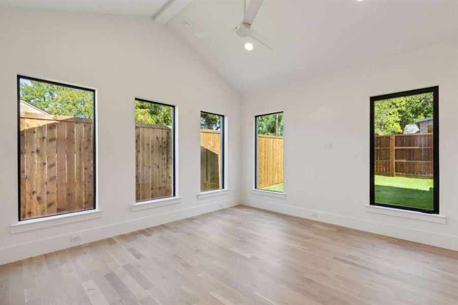 Unfurnished room featuring light wood-type flooring, beam ceiling, ceiling fan, and high vaulted ceiling