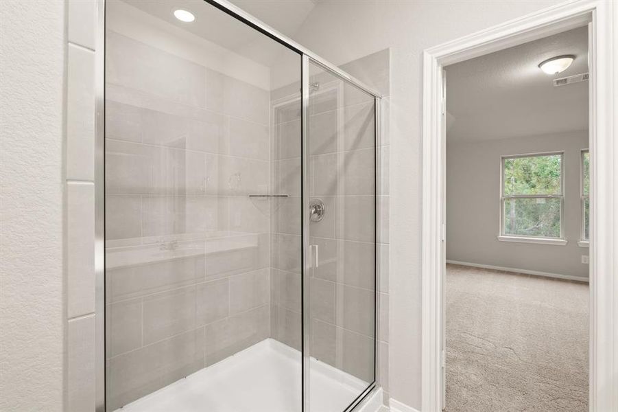 This additional view of your primary bathroom features tile flooring, fresh paint, and a large walk-in shower.