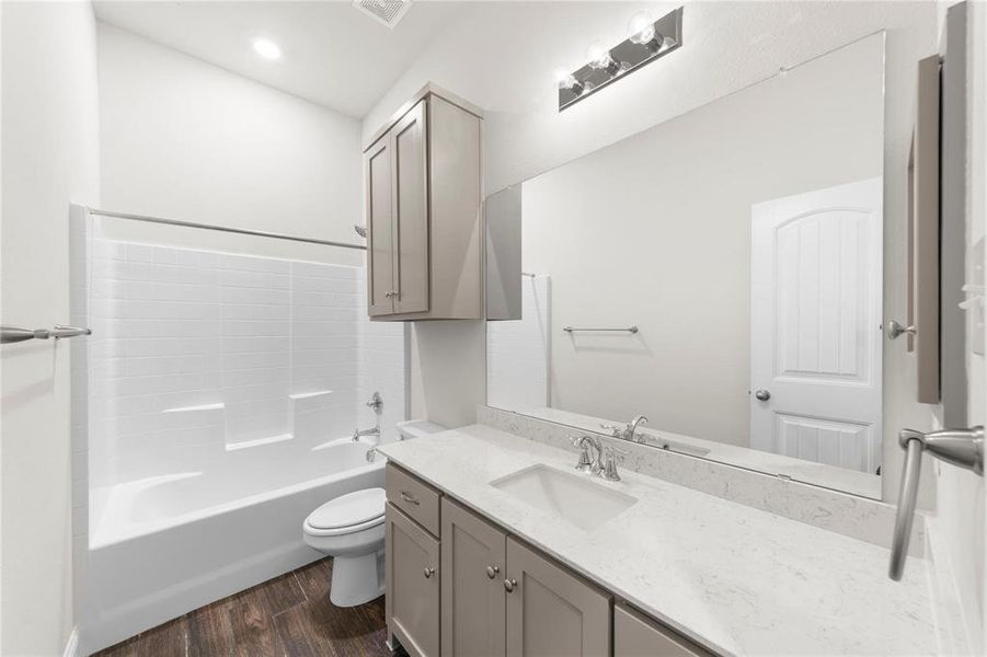 Full bathroom with wood-type flooring, shower / washtub combination, vanity, and toilet