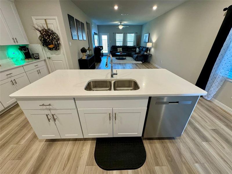 Kitchen with white cabinets, sink, a kitchen island with sink, and light hardwood / wood-style flooring