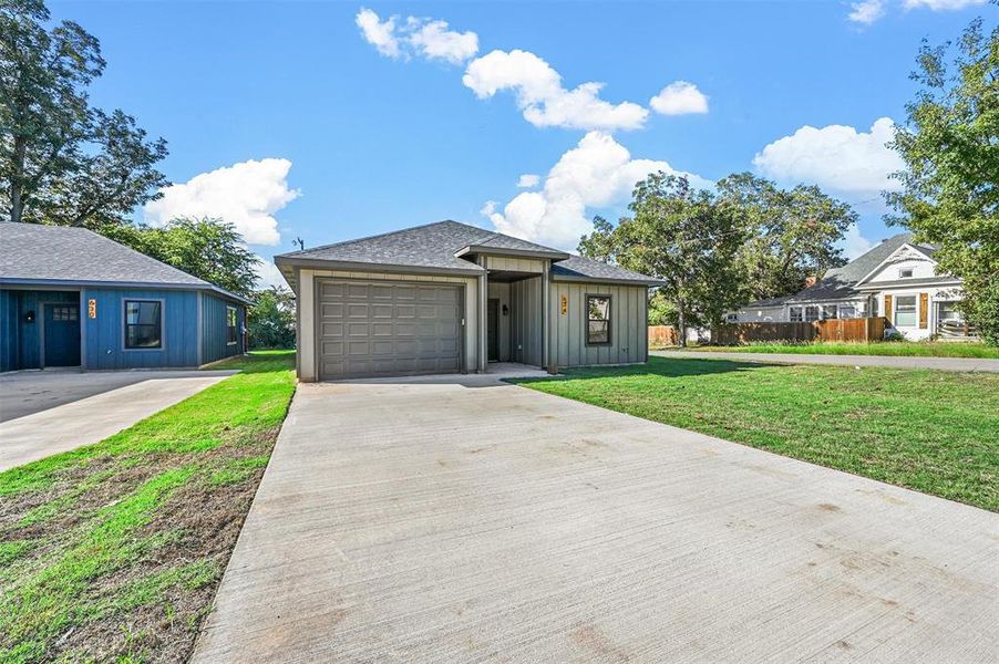 View of front of property with a front yard and a garage