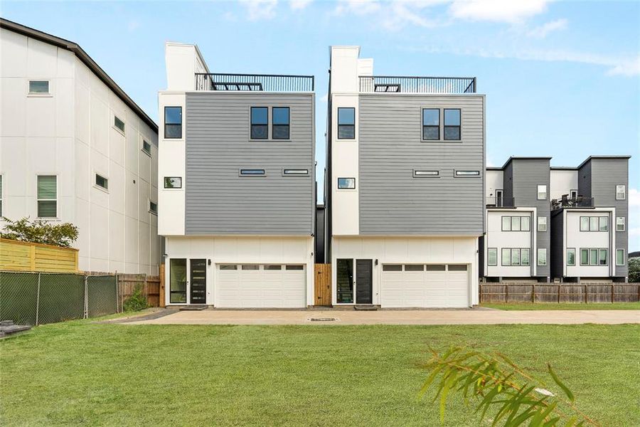 Modern townhomes with gray siding, featuring multiple levels, rooftop terraces, and attached garages.