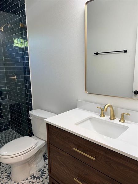 Bathroom featuring toilet, vanity, tile patterned floors, and tiled shower